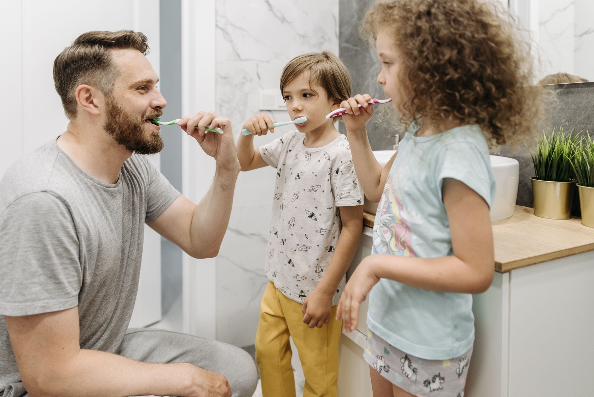 A parent and children brushing their teeth together